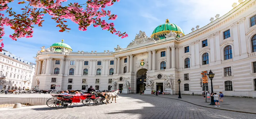 Palatul Hofburg cu cupole verzi, trăsură cu cai și cireși înfloriți, Viena Austria - zboruri ieftine TravelTheme