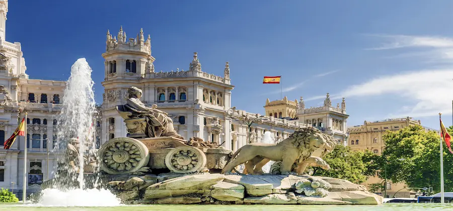 Detaliu sculptural cu leu și jet de apă, Plaza de Cibeles cu steag spaniol, vacanță Madrid - oferte hoteluri