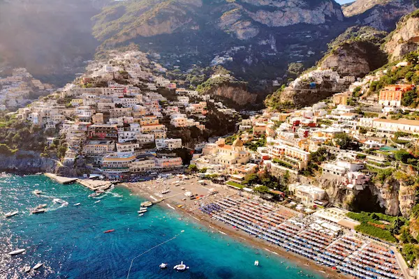 Positano pe Coasta Amalfitană cu case colorate pe stâncă și plajă cu umbrele — sejur charter Italia