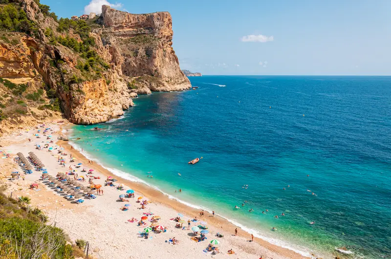 Cala del Moraig pe Costa Blanca, plajă cu pietriș alb sub stânci abrupte — sejur charter Spania Alicante