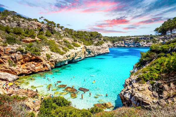 Cala Llombards din Mallorca la apus, golf îngust cu apă turcoaz între stânci — sejur charter Spania, Baleare